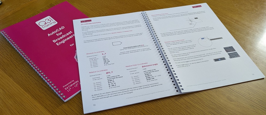AutoCAD Booklet Closeup of 2 training books, one with open pages showing mostly text content describing functions of AutoCAD