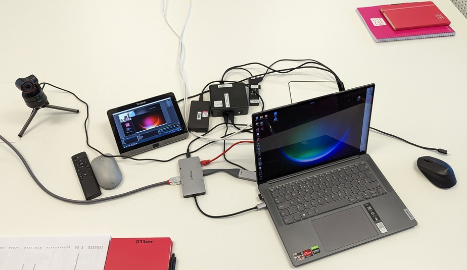 Training Recording Kit 2 A laptop computer, small NUC PC and webcam with lost of connecting wires. The laptop screen can also be seen embedded on the small screen next to it which is being used to record it and the camera