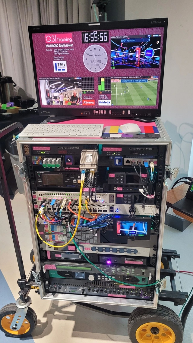 BigPinkDemoKit-IP Small equipment rack on a trolley containing lots of broadcast equipmnent with a video monitor on the top showing a TAG multiviewer display of SMPTE 2110 signals