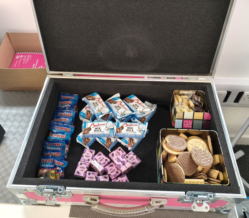 oplus_2097152 The Big Pink Snackbox (pink flightcase with a briefcase opening style) containing biscuits, haribo, raisins, cake bars and sweets